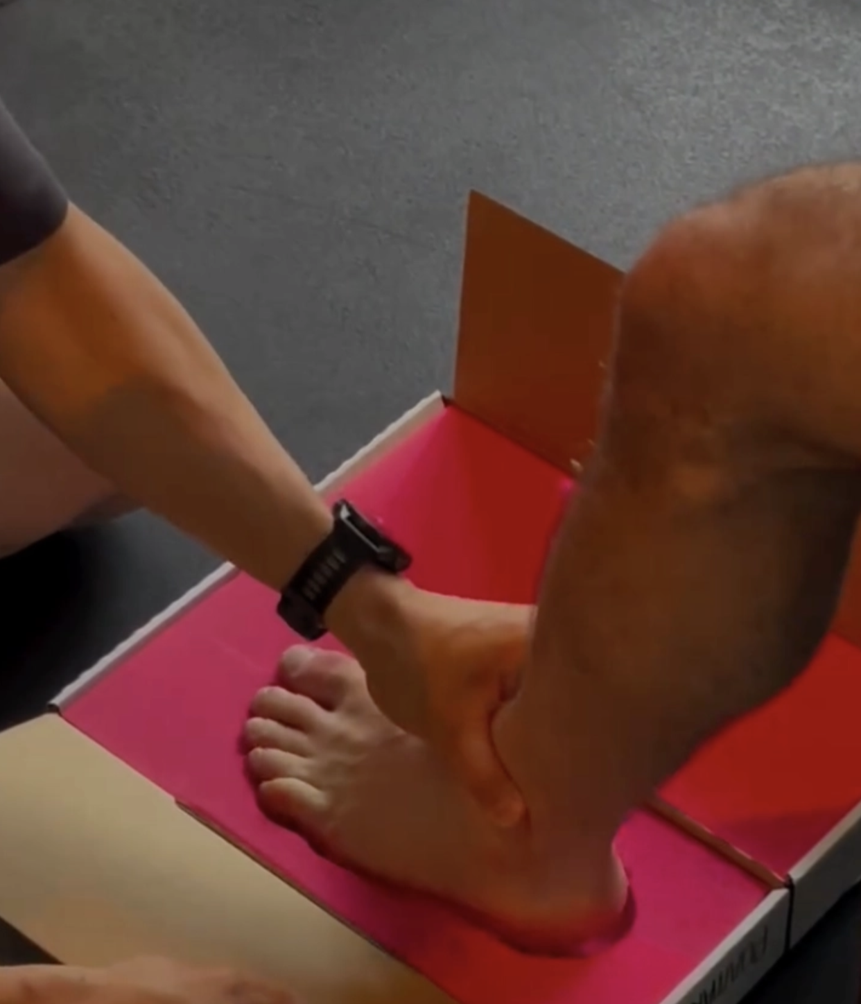 Geoff being fitted for orthotics, his bare foot pressed onto a bright pink measuring form